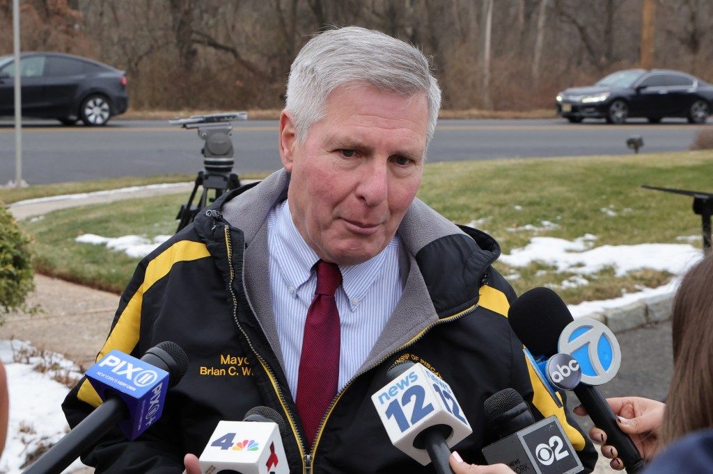 Piscataway Mayor Brian C. Wahler speaks to the media with microphones from Pix11, NBC4, News12, CBS2, and ABC7 visible.